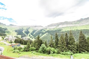 Eine gebirgige Landschaft mit einer Straße, Gebäuden und dichtem Wald.