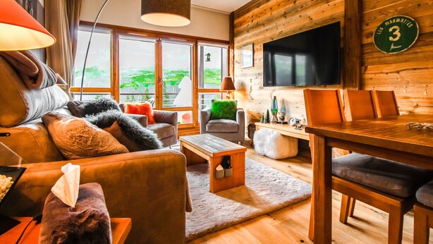 Een gezellige woonkamer met een bank, fauteuils, een salontafel en een televisie.