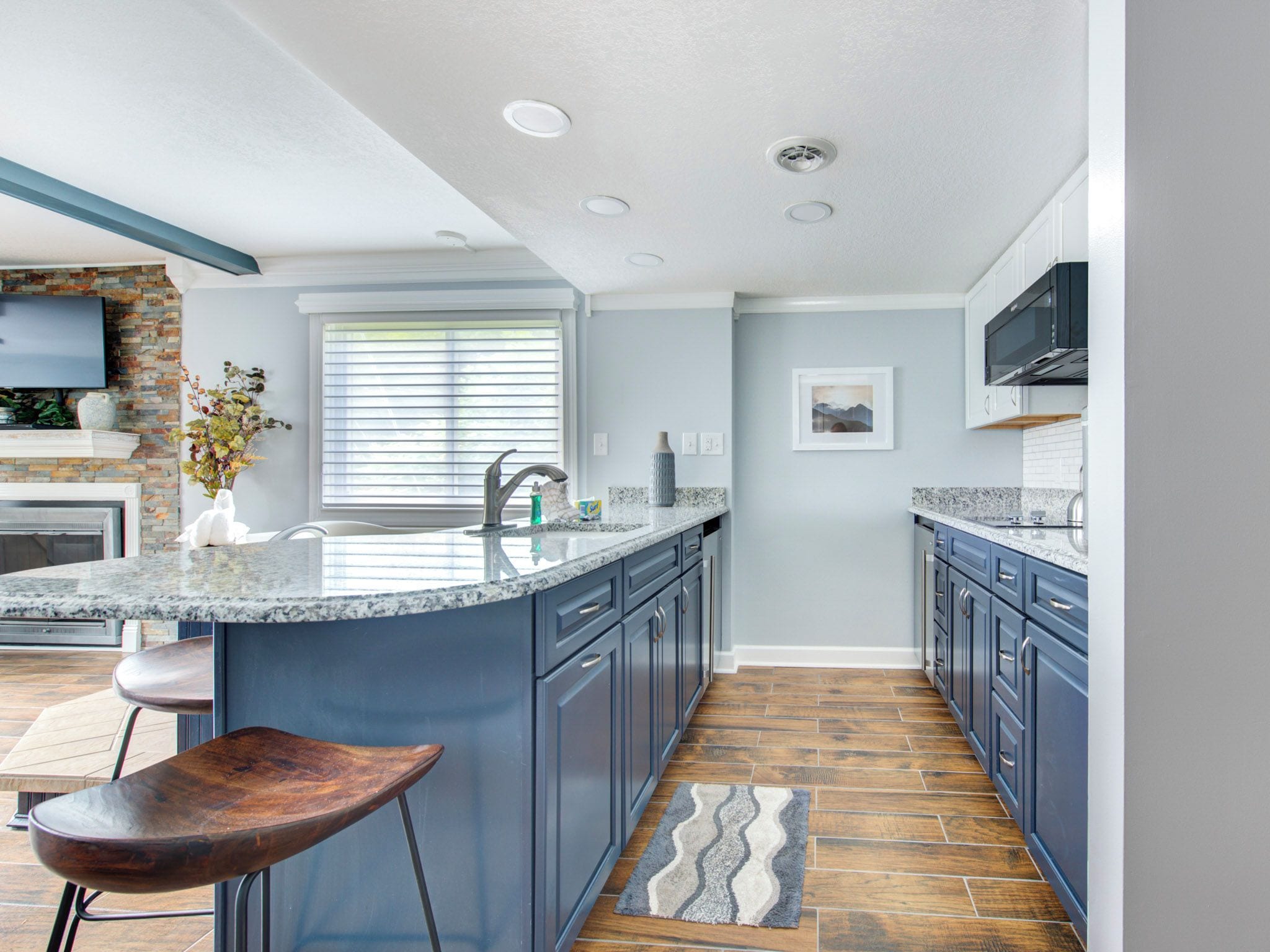 Una cocina moderna con encimeras de granito, una isla integrada y armarios de color azul oscuro.
