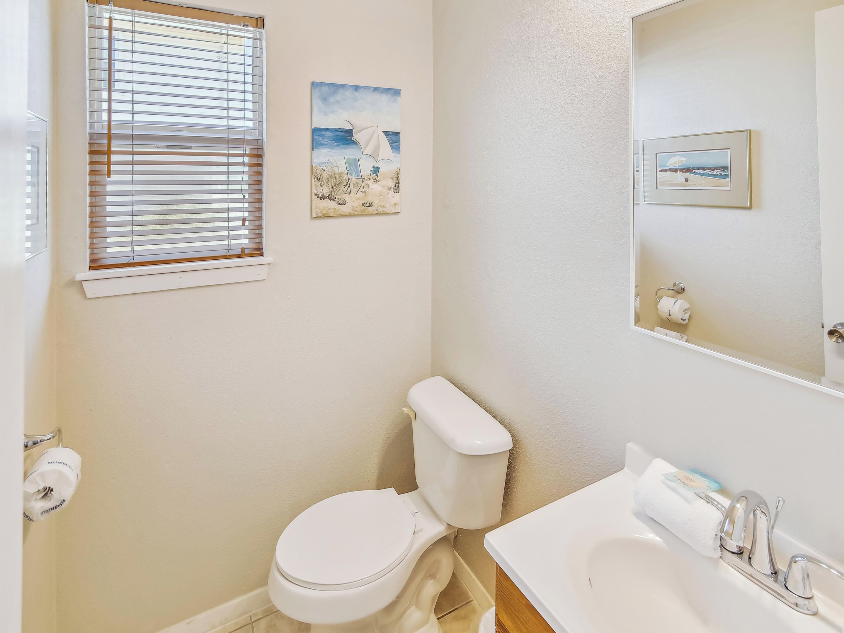 A bathroom with a toilet, sink, and window with blinds.