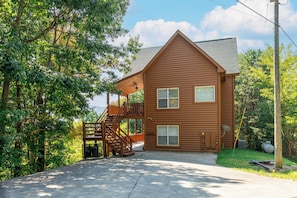 A two-story log cabin with a covered porch and a staircase leading to the upper level.
