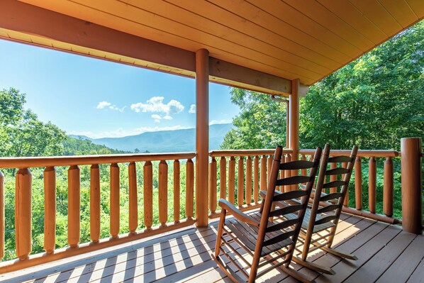 A wooden deck with a railing overlooking a mountainous landscape.