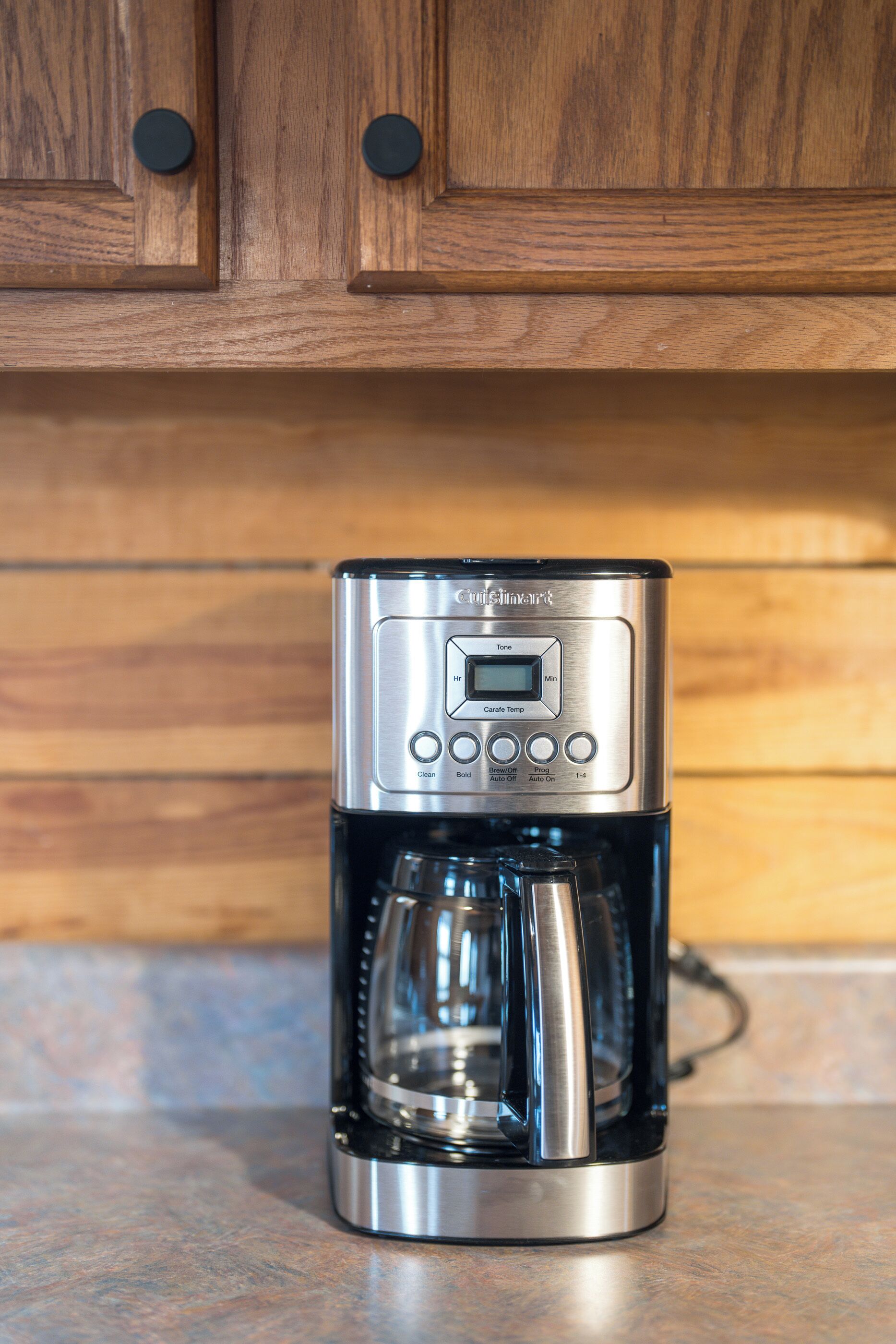 A coffee maker with a digital display and control buttons, placed on a countertop.