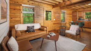 Un intérieur de chalet chaleureux avec un canapé en cuir, une table basse et un coin repas.