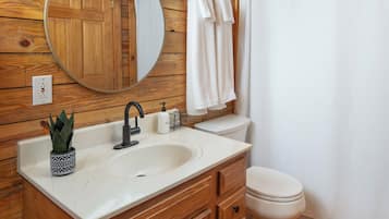A wooden bathroom with a sink, mirror, and toilet.