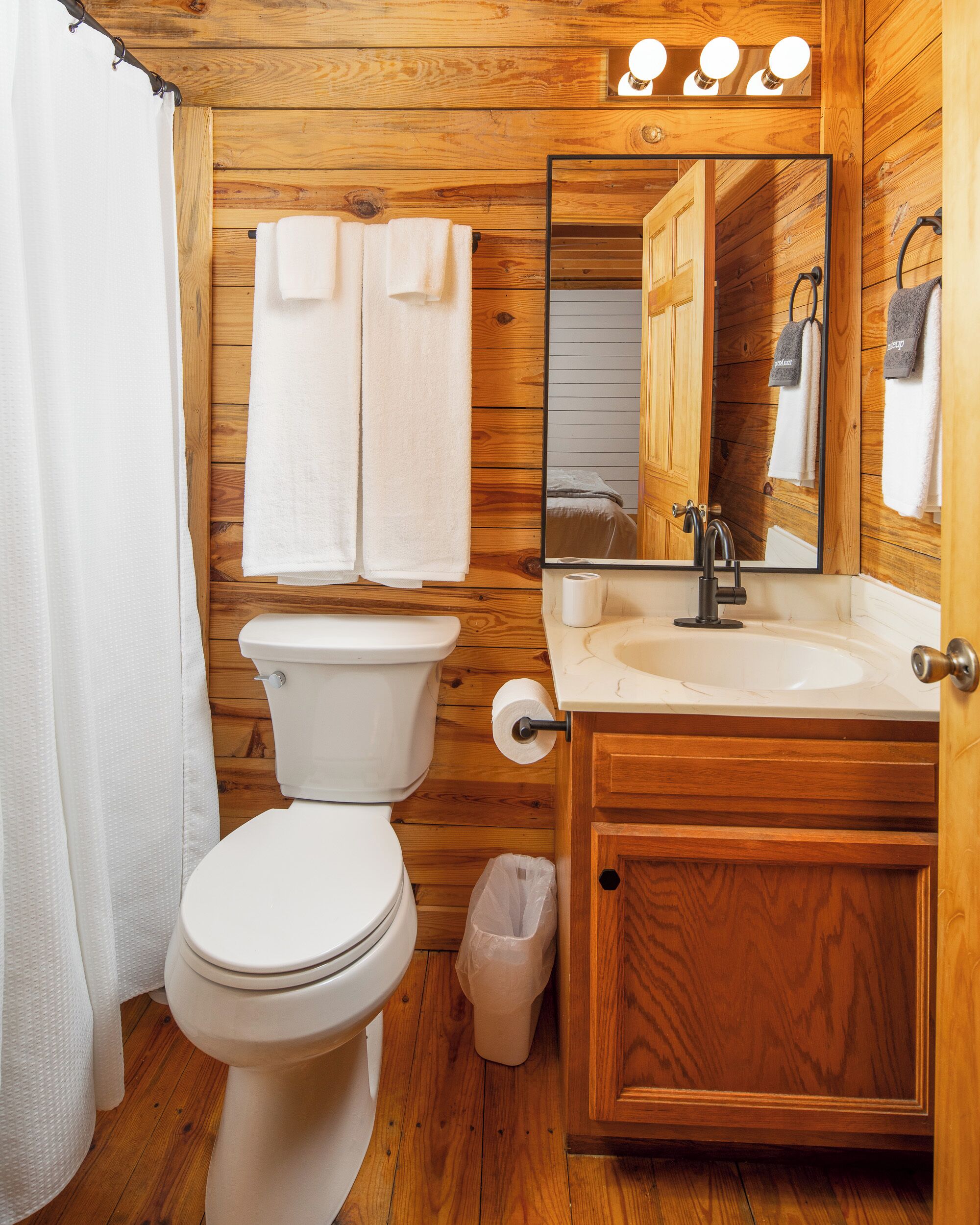 Un baño de madera con inodoro, lavabo y espejo.