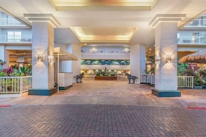 A spacious lobby with a central reception desk, multiple floors visible, and a tropical plant display.