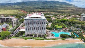 Un hotel con piscina, acceso directo a la playa y montañas al fondo.