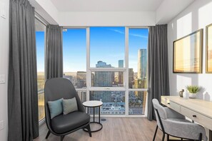 Ein modernes Zimmer mit großem Fenster, Schreibtisch, zwei Stühlen und einem kleinen Tisch.