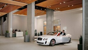 Tilava aula, jossa on valkoinen avokattoinen Bentley-auto pysäköitynä vastaanottotiskin läheisyyteen.