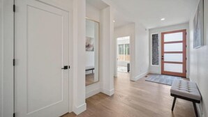 A hallway with a wooden floor, a bench, and a door with frosted glass panels.