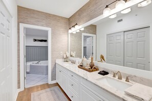 Une salle de bain moderne avec un grand miroir, un meuble-lavabo et une baignoire.