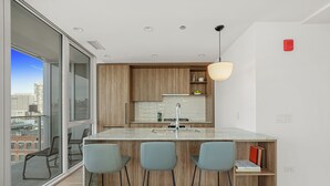 Une cuisine moderne dotée d’un grand îlot central, de tabourets de bar et offrant une vue sur la ville.