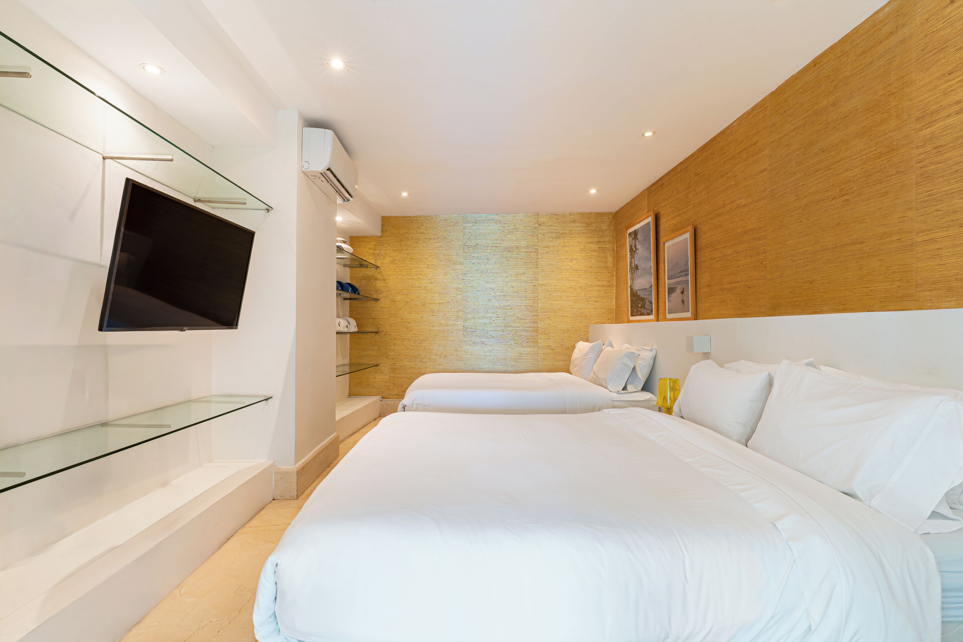 Quarto de hotel moderno com uma cama grande, televisão de tela plana na parede e uma parede de destaque em madeira.