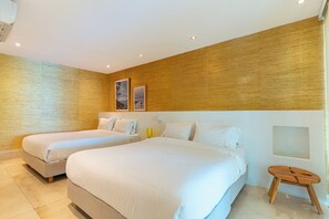 Habitació d'hotel amb dos llits, una paret decorativa de fusta i un petit tamboret.