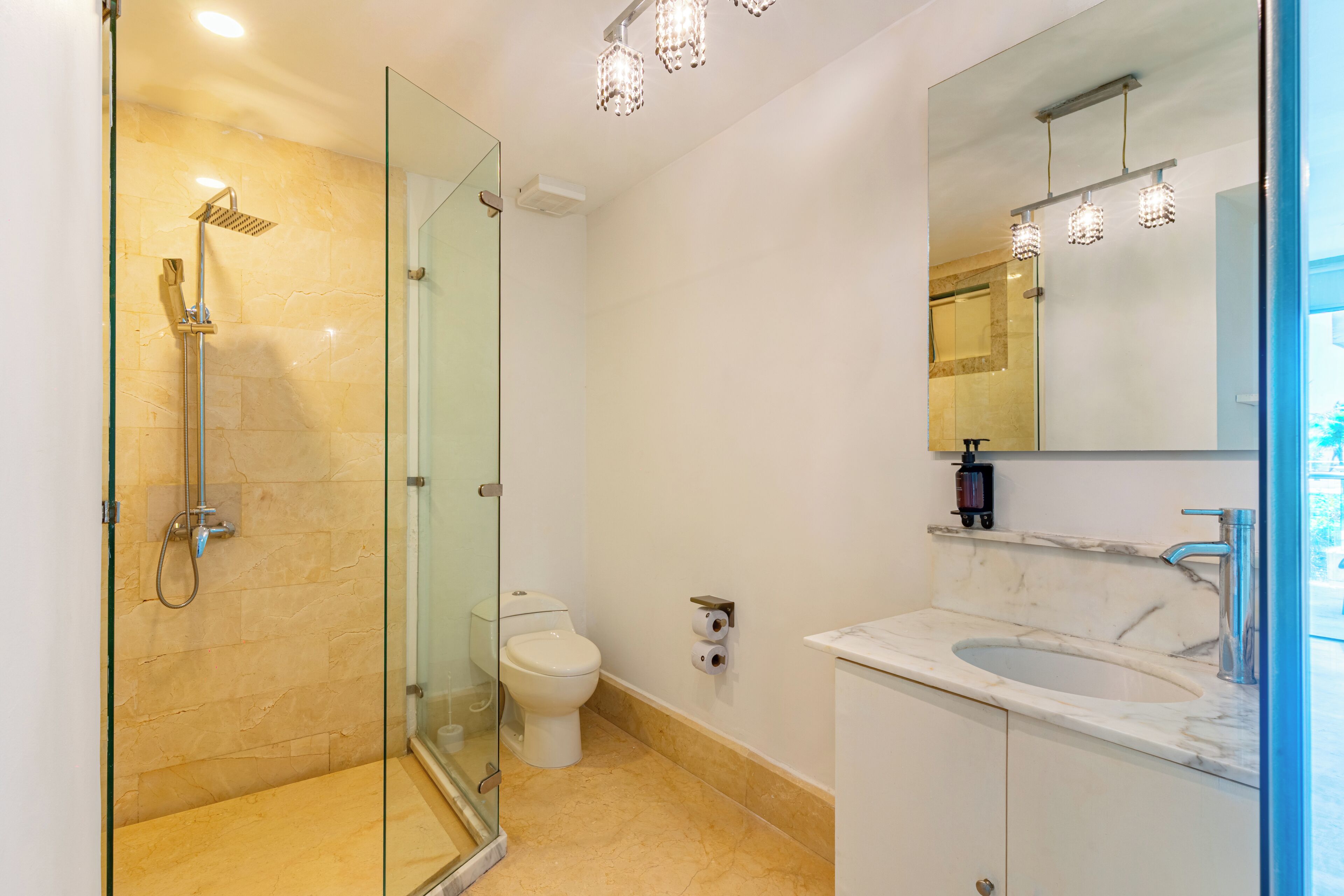 A modern bathroom with a glass-enclosed shower, a toilet, and a sink with a marble countertop.