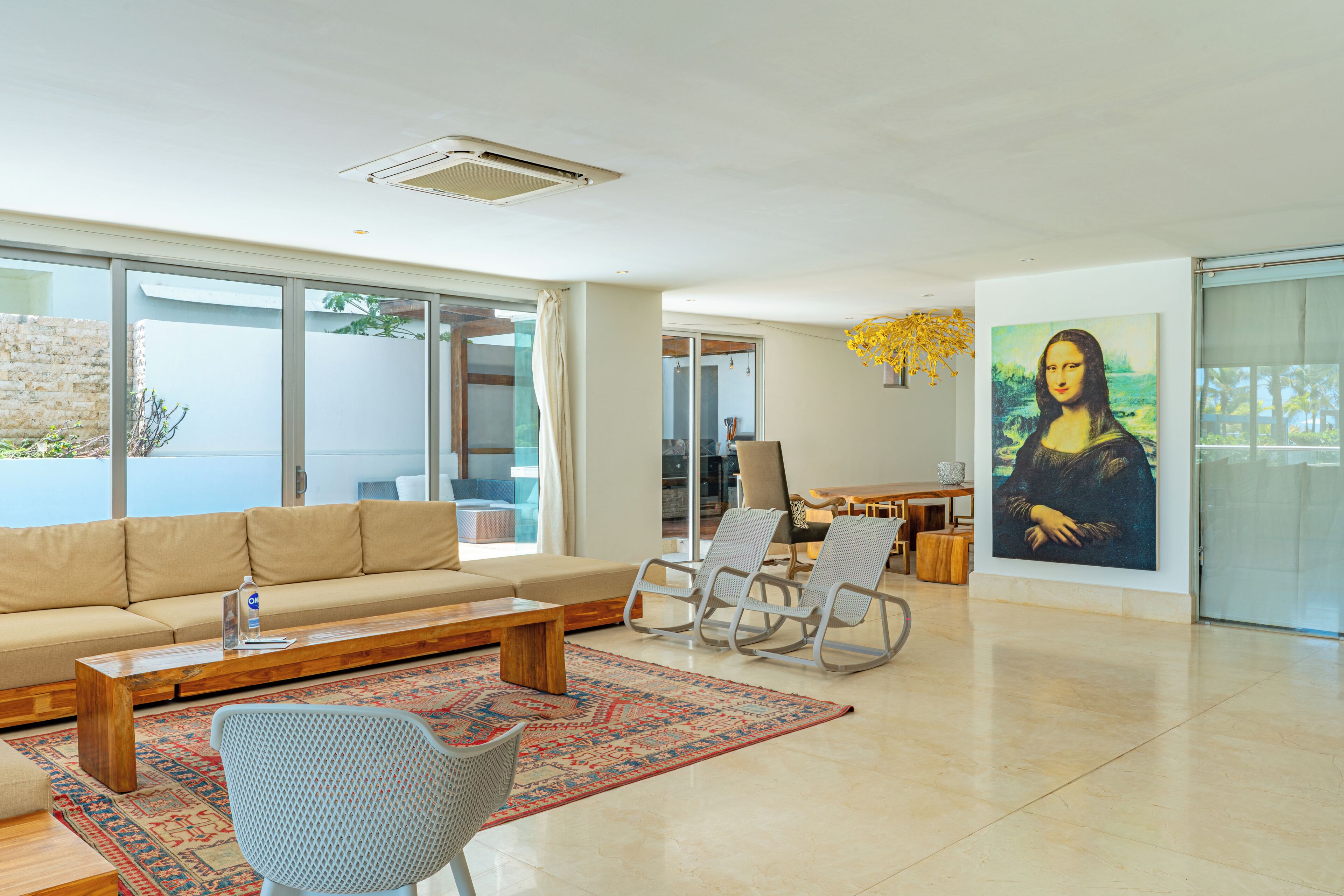 Una sala de estar moderna con sofá, sillas, una mesa de centro y un cuadro grande de la Mona Lisa.