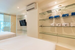A hotel room with a bed, a TV, and glass shelves with towels. - Wynwood Morros Epic in Cartagena (Cartagena)