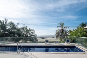 A swimming pool with a glass railing, palm trees, and a view of the beach. - Wynwood Morros Epic in Cartagena (Cartagena)