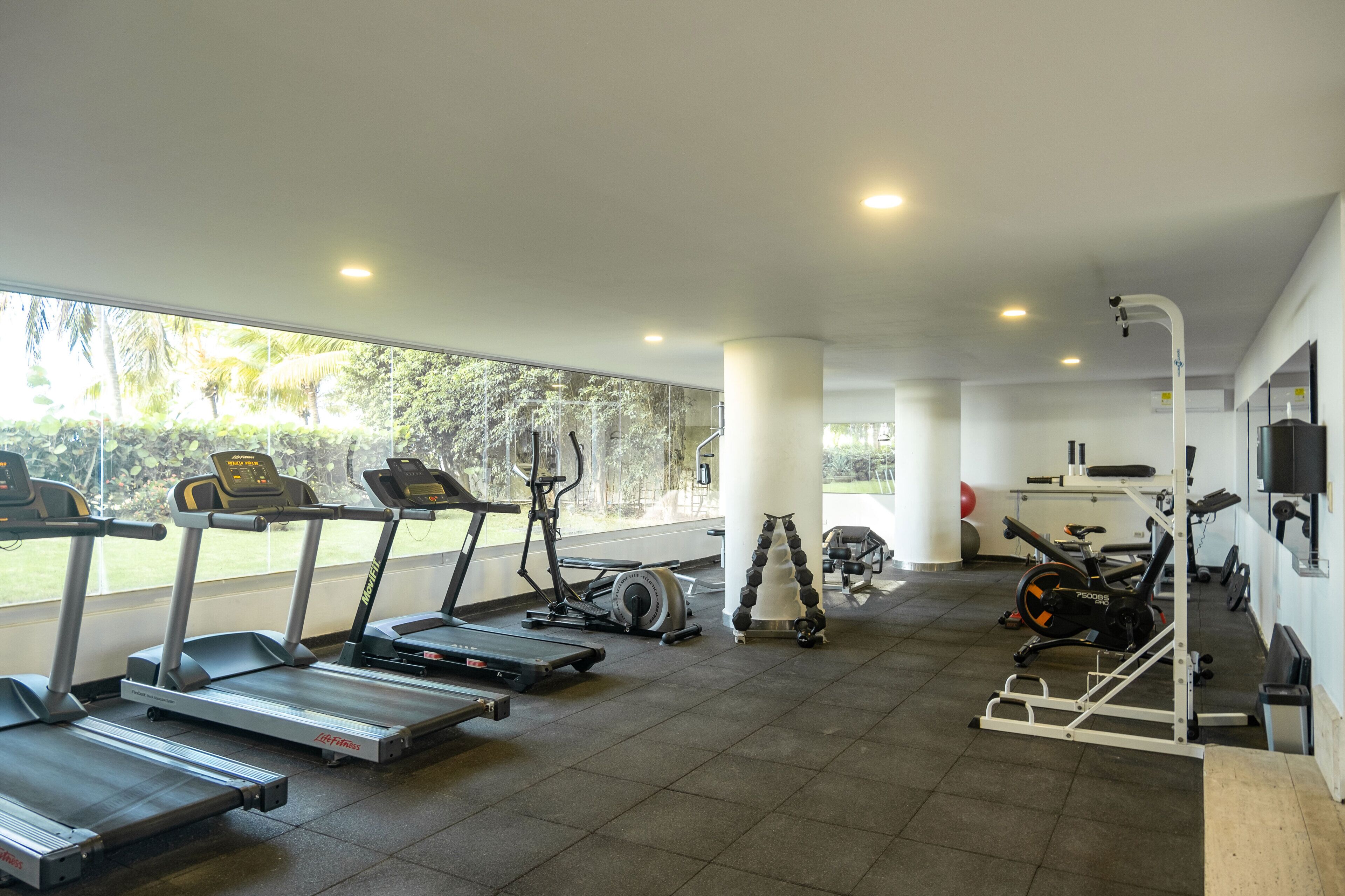 Un gimnasio con cintas de correr, elípticas y equipo de pesas.