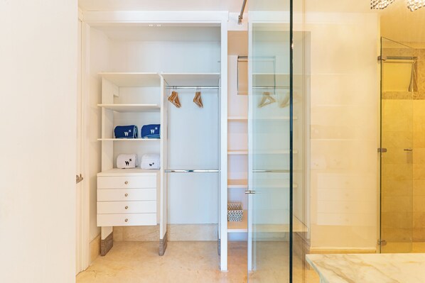 A walk-in closet with open doors, a glass shower enclosure, and a marble-tiled floor. - Wynwood Morros Epic in Cartagena (Cartagena)