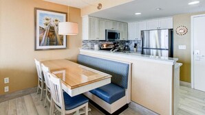 Cocina compacta con comedor, que incluye un microondas, refrigerador y una banca.