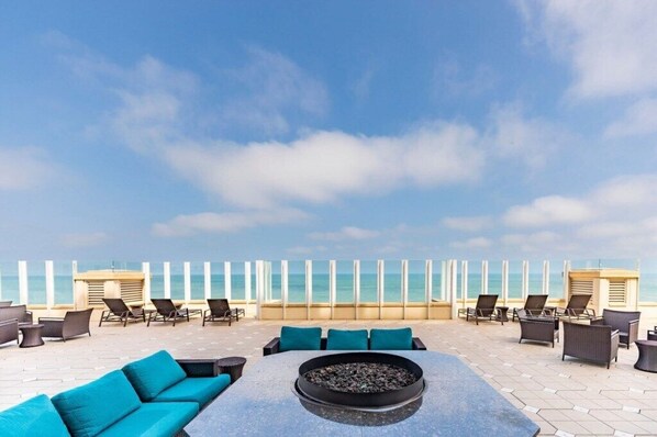 Relax on the rooftop terrace with ocean views, surrounded by lounge chairs and a sofa.