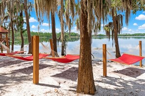 Una playa con hamacas y una cubierta de madera con vistas a un lago tranquilo.