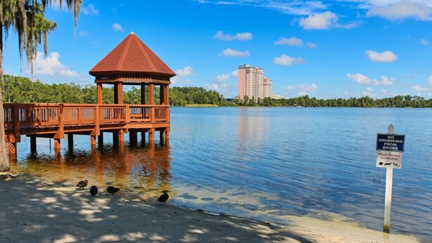 Ein hölzerner Pavillon an einem See, mit einem Schild, das das Schwimmen vom Ufer aus verbietet.
