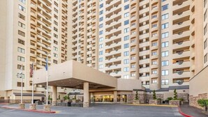 Un hotel moderno de gran altura con entrada central, varios balcones y un asta de bandera.