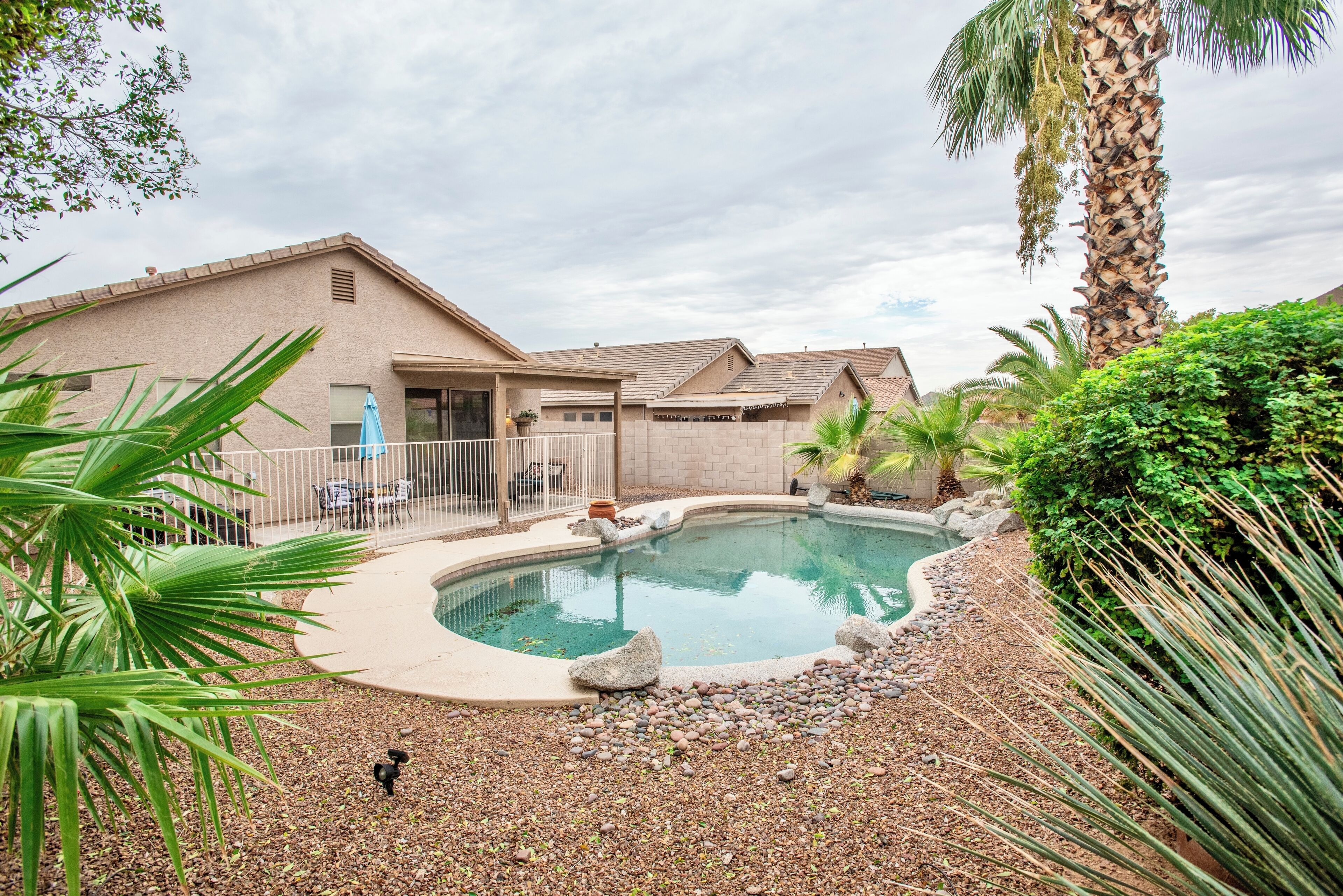 A residential property with a swimming pool, a covered patio, and a well-maintained garden.