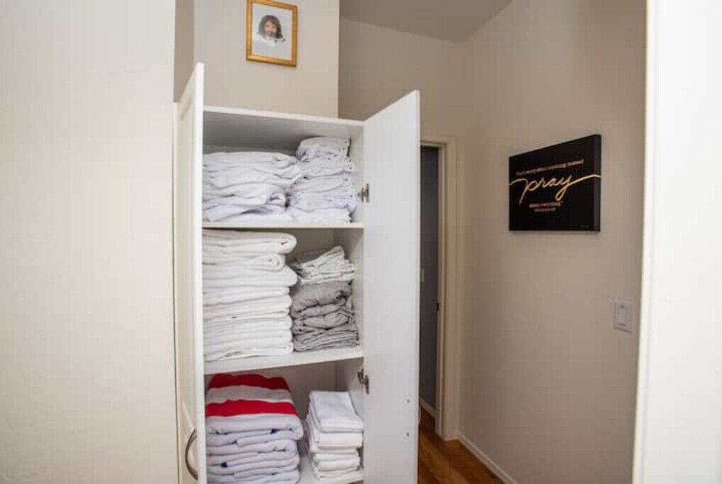 A neatly organized closet with folded towels and a framed sign on the wall.