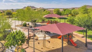 A playground with slides and swings, surrounded by trees and a clear sky. - Poolside Paradise Terramar Family Safe Retreat Beautiful Northwest Peoria (Peoria)