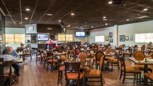 Ein Restaurant mit mehreren Tischen und Stühlen, einer Bar mit Fernseher und einer Theke.