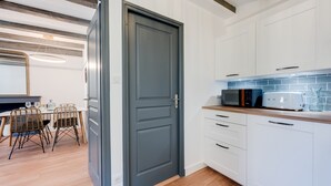 Een moderne keuken met witte kastjes, een donkergrijze deur en een houten aanrecht.