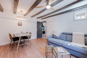 A modern living room with a dining table, blue sofa, and a ceiling fan.