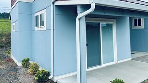A single-story building with a light blue exterior, a red roof, and a small porch area.