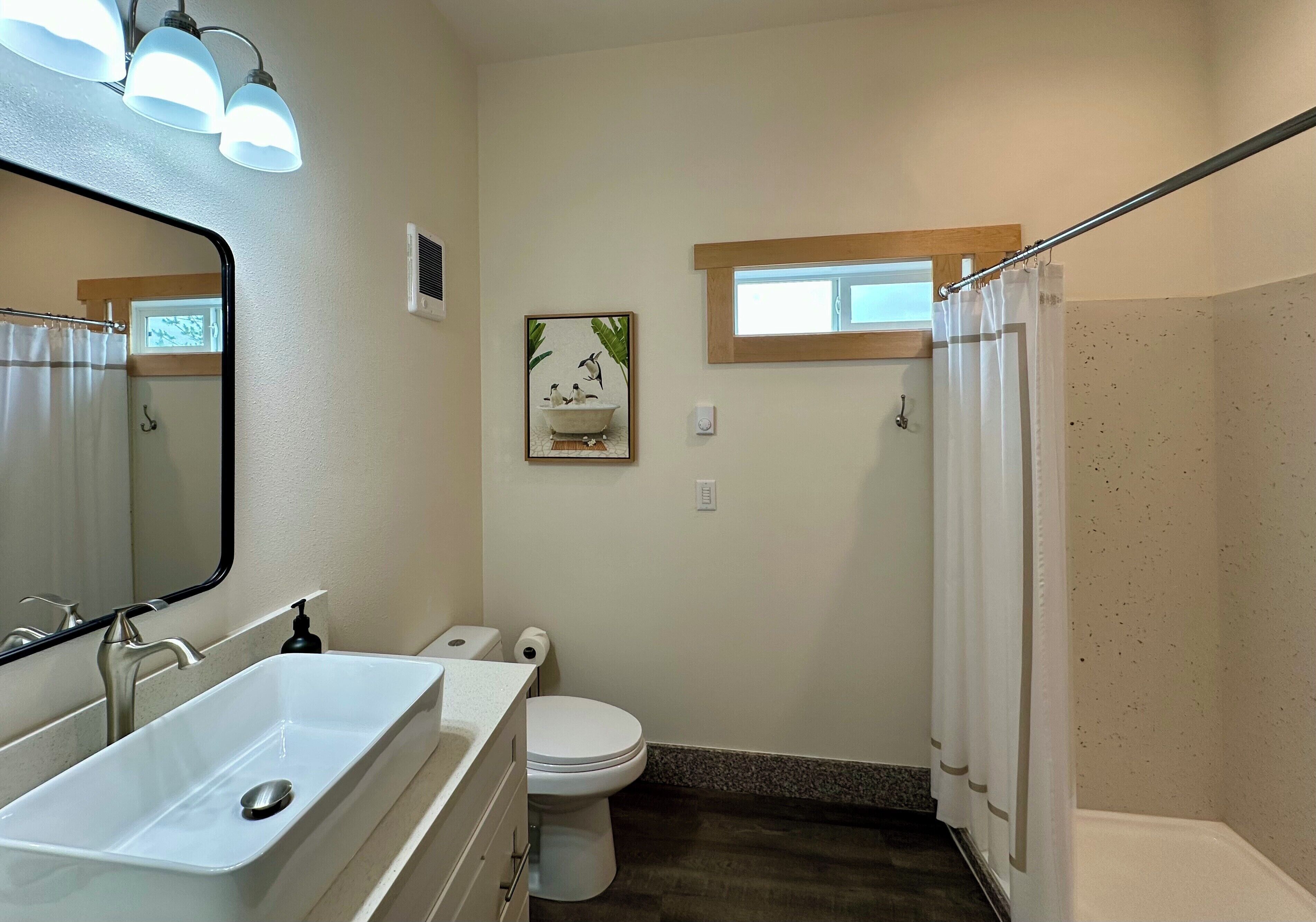 Un bagno con lavandino, wc e zona doccia bianchi.