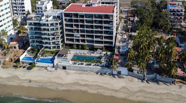 A multi-story hotel with a rooftop pool and beachside view.