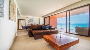 A modern living room with a brown sofa, a wooden coffee table, and a view of the sea through large glass doors. - Casa del Mar by Kivoya (Bucerías)