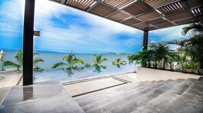 A modern outdoor terrace with a clear view of the ocean and a distant coastline.