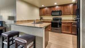 A compact kitchen with a granite countertop, stainless steel appliances, and wooden cabinets.