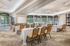 A conference room with tables and chairs, large windows, and a high ceiling.