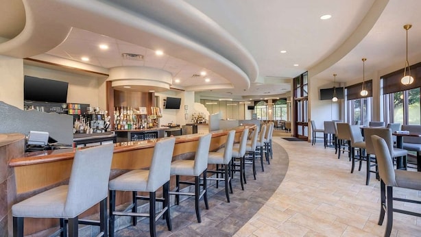 A bar area with multiple seating options, a counter with a variety of bottles, and a television screen.