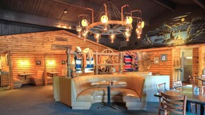 L’intérieur d’une cabane en rondins comprend un espace salon central, une table à manger et un lustre.