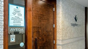 A spa entrance with a wooden door, a sign listing services like massages and facials, and a logo for 'sapphirespa'. - Beachfront Vacation Condo at the Sapphire (South Padre Island)