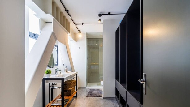Ein modernes Badezimmer mit Glasdusche, einer Holzbank und einem Waschbecken mit Spiegel.
