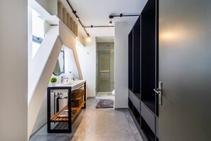 Un baño moderno con ducha de vidrio, un banco de madera y un lavamanos con espejo.