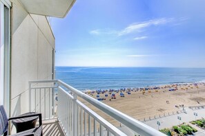 Uma varanda com vista para uma praia com guarda-sóis e pessoas.