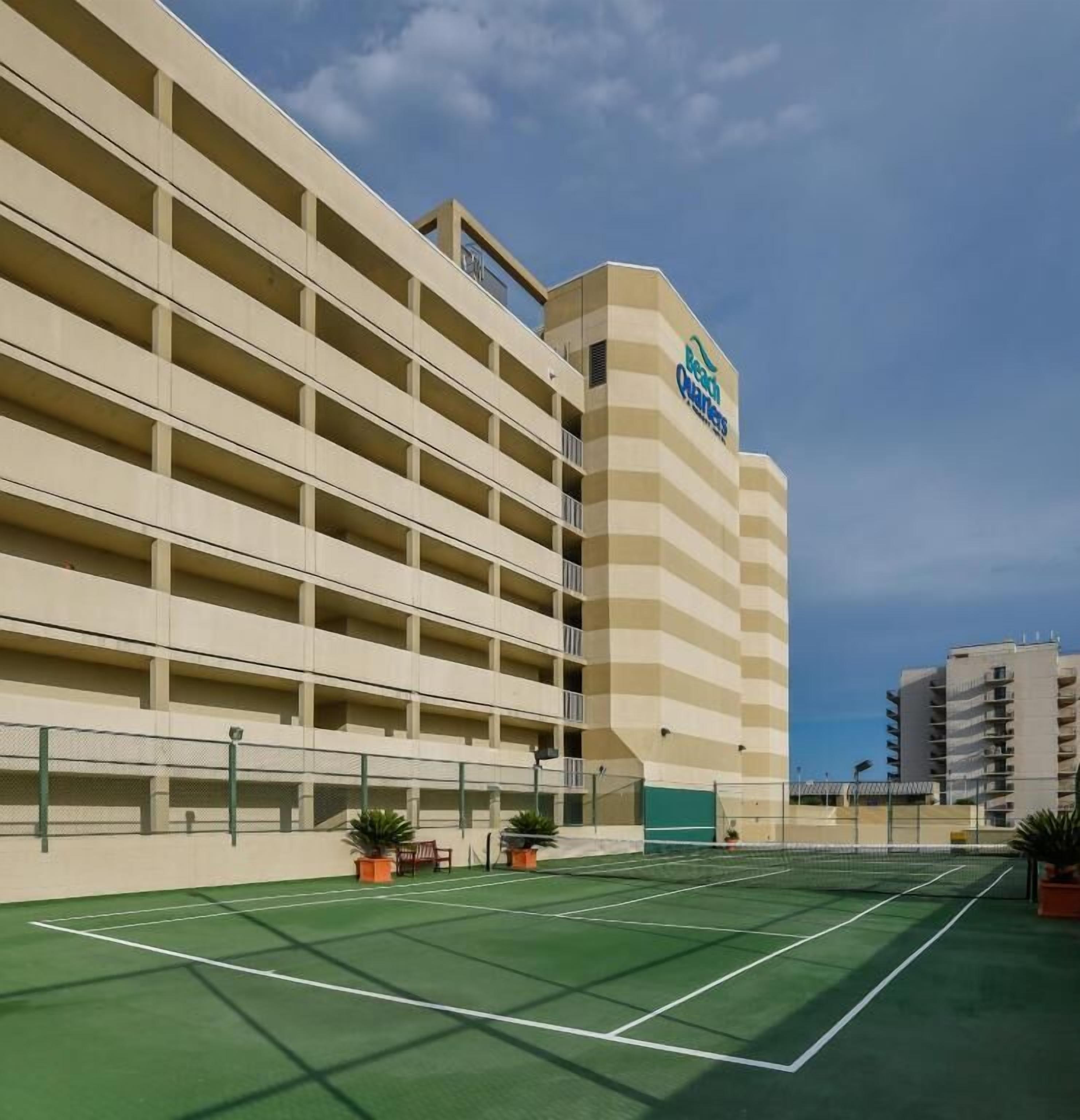 Un hôtel à plusieurs étages doté d’un grand parking et d’un court de tennis.